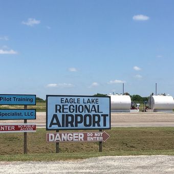 Sign for Eagle Lake Regional Airport under a blue sky, with white tanks in the background.