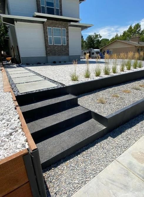 Exterior view of a house with a walkway. Steps, stone path, and decorative gravel are in front of the modern home.