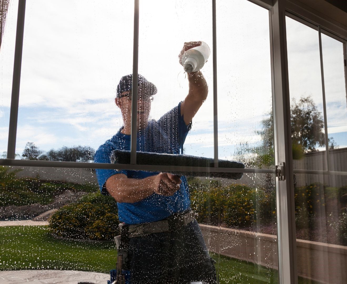 A man in a blue shirt is cleaning a window