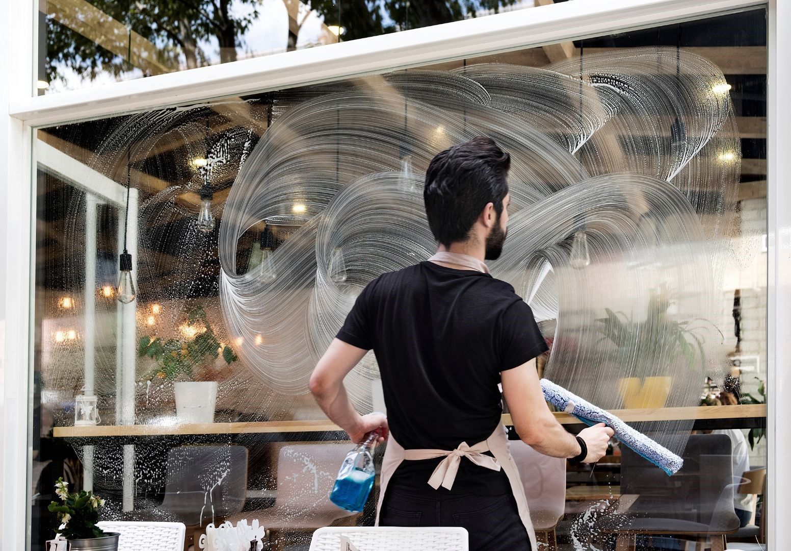 A man is cleaning a window with a spray bottle.
