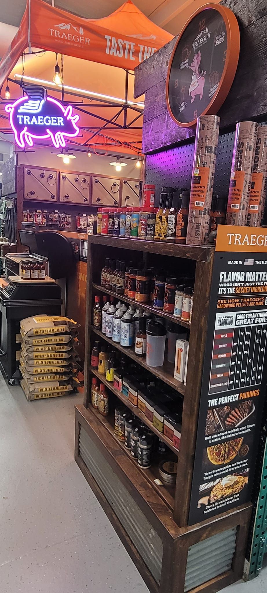 A store display with barbecue sauces and rubs. A neon pig sign hangs above.