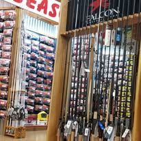Fishing rods displayed in a shop aisle beside hanging tackle packages