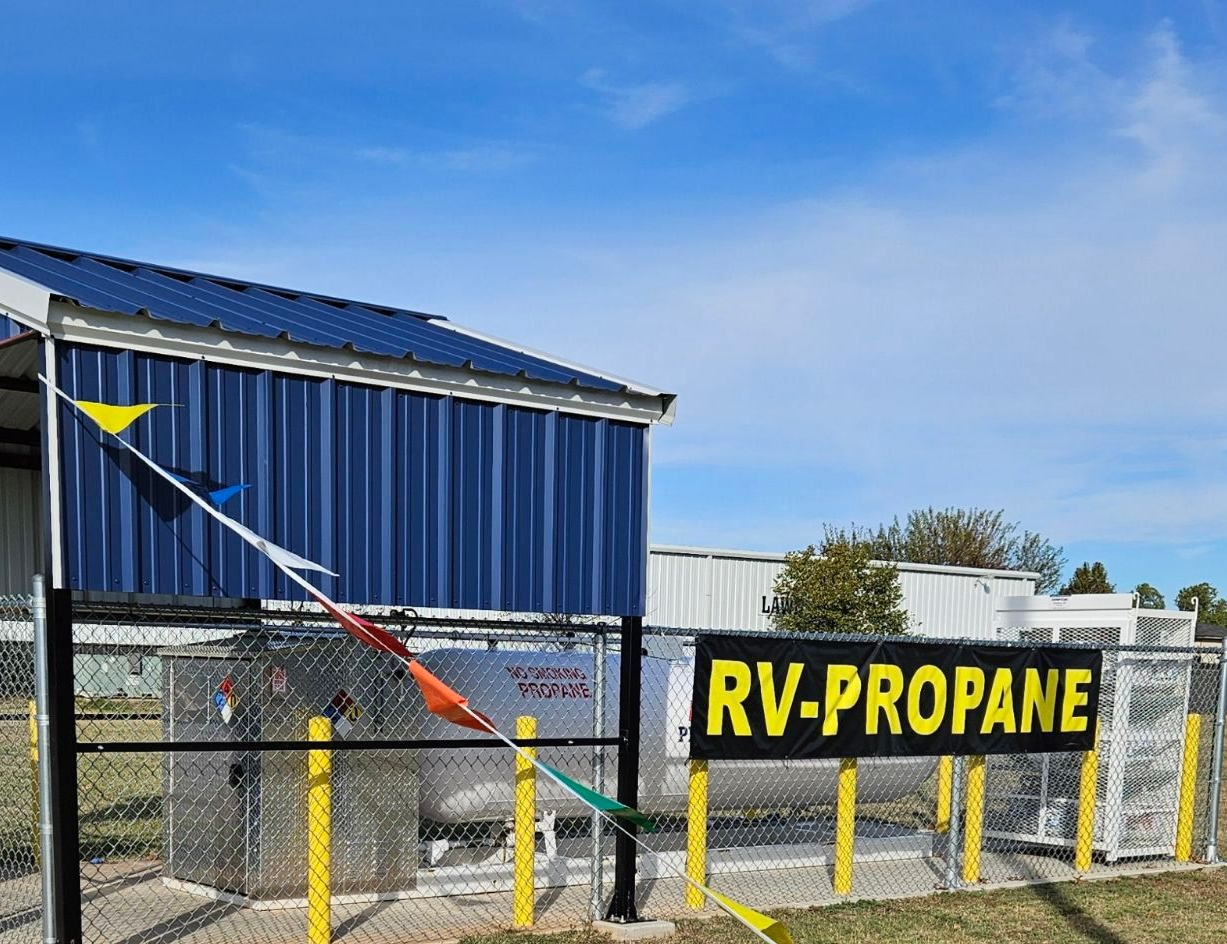 RV propane filling station, blue building, fenced area, yellow and black sign, blue sky.