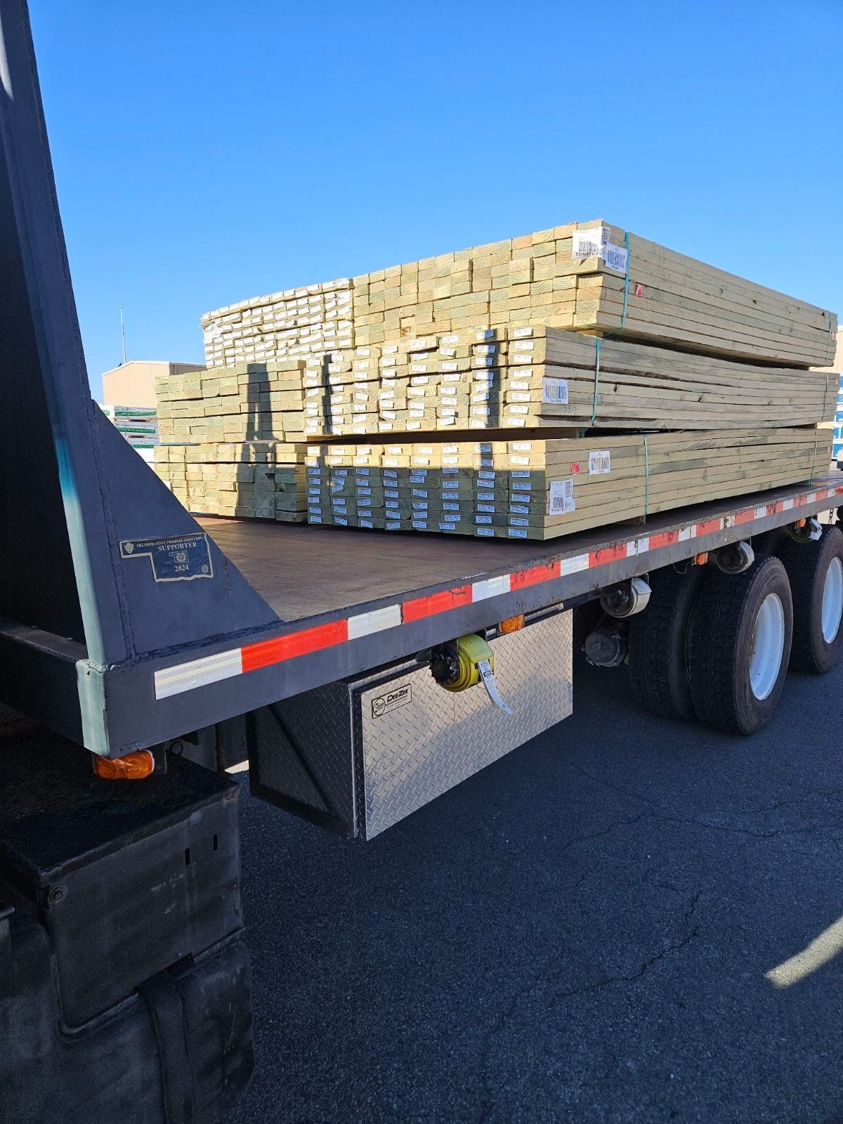 Flatbed truck loaded with lumber on a sunny day.