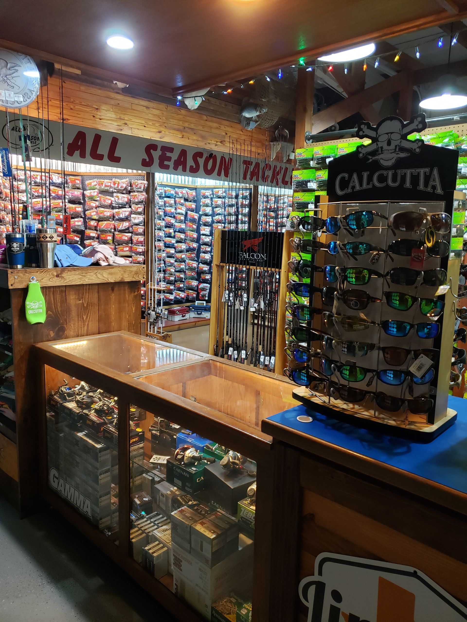Inside a fishing tackle store; display of sunglasses and fishing rods. 