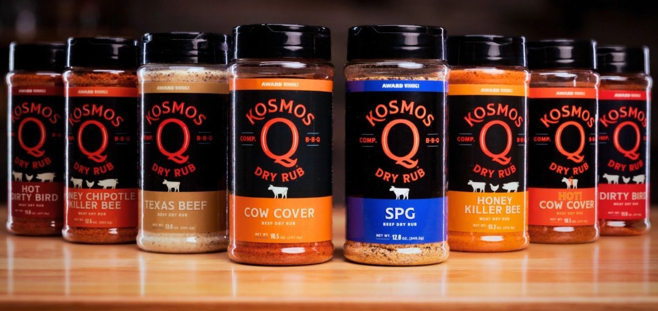 Several Kosmos Q Dry Rub spice jars lined up on a wooden surface.