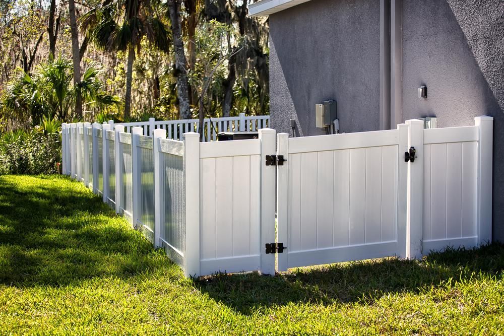 a White Fence With a Black Gate is in the Grass in Front of a House — Tony Sinclair Fencing In Dorrigo, NSW