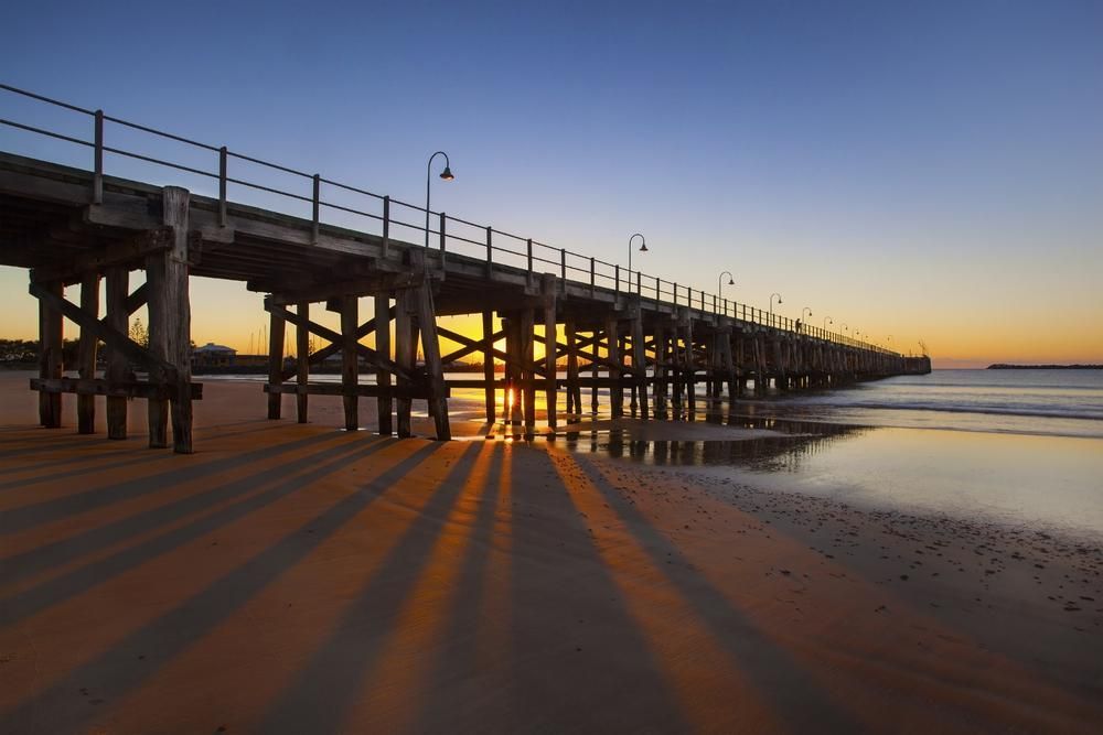 a Pier Leading Into the Ocean at Sunset — Tony Sinclair Fencing In Coffs Harbour, NSW