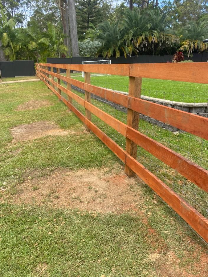 a Wooden Fence is Sitting in the Middle of a Lush Green Field — Tony Sinclair Fencing In Bucca, NSW