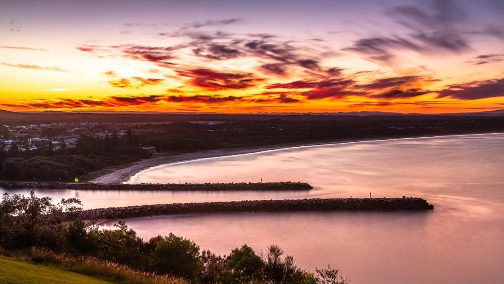 a Sunset Over a Body of Water With a City in the Distance — Tony Sinclair Fencing In Inverell, NSW