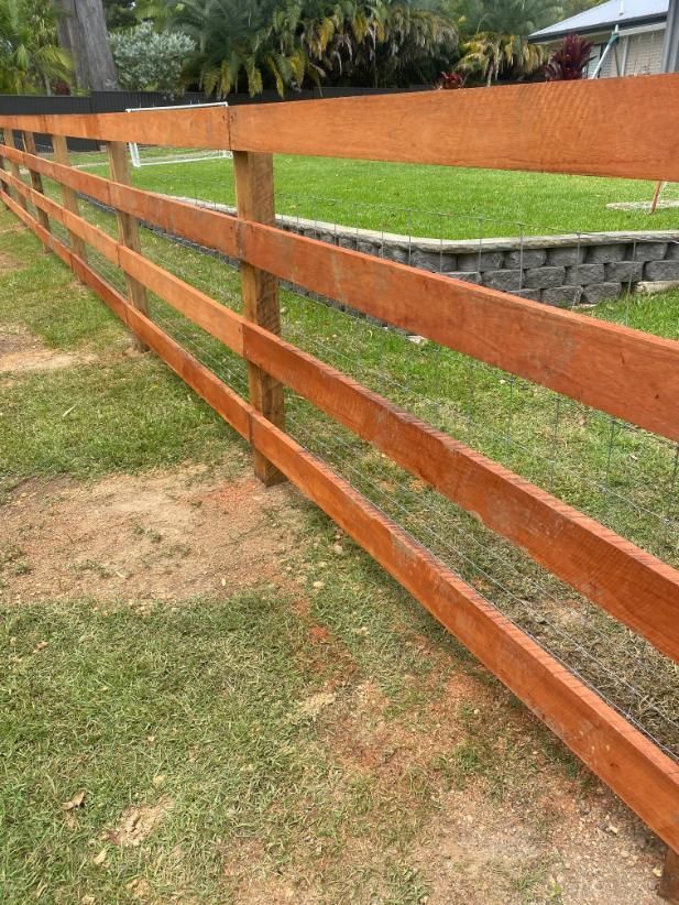 a Wooden Fence is Sitting in the Middle of a Lush Green Field — Tony Sinclair Fencing In Inverell, NSW