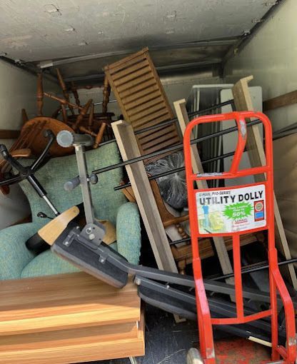 Movers using a hand truck to carefully transport a refrigerator within an apartment.