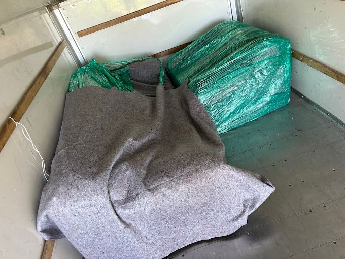 Worker from a moving company unloading items from the back of a truck.