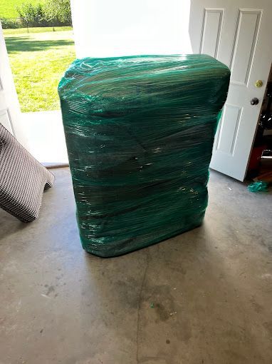 Mover using scotch tape to wrap a cardboard box in an apartment, preparing for a move.