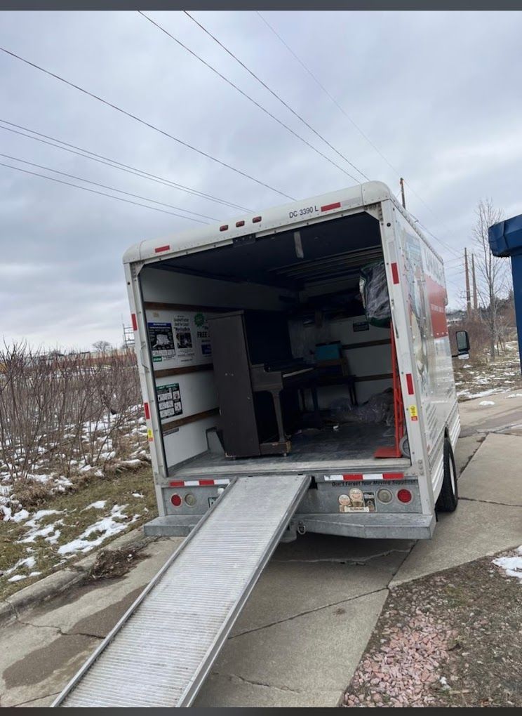 Two cheerful delivery professionals collaborating to load a cardboard box into a delivery van, ensuring a smooth and efficient process.