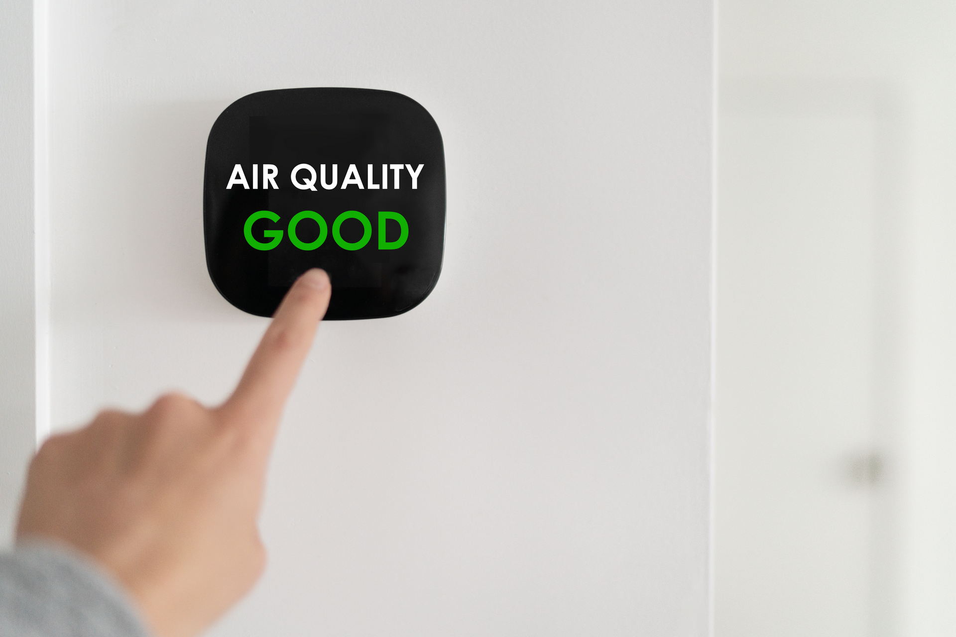 A person is pressing a button on a wall that says `` air quality good ''.