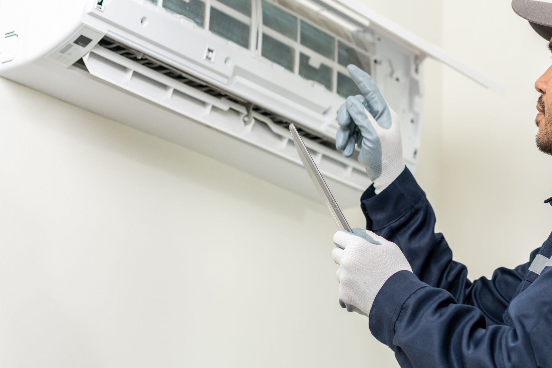 A man is fixing an air conditioner with a wrench.