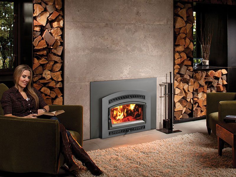 A woman is sitting in a chair in front of a fireplace.