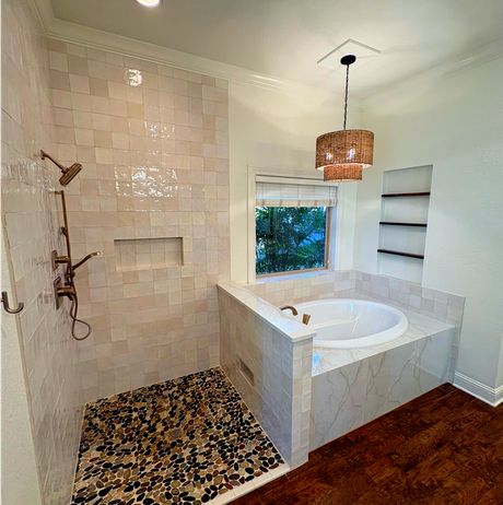Bathroom with stone shower floor, tiled walls, tub, and hanging light.