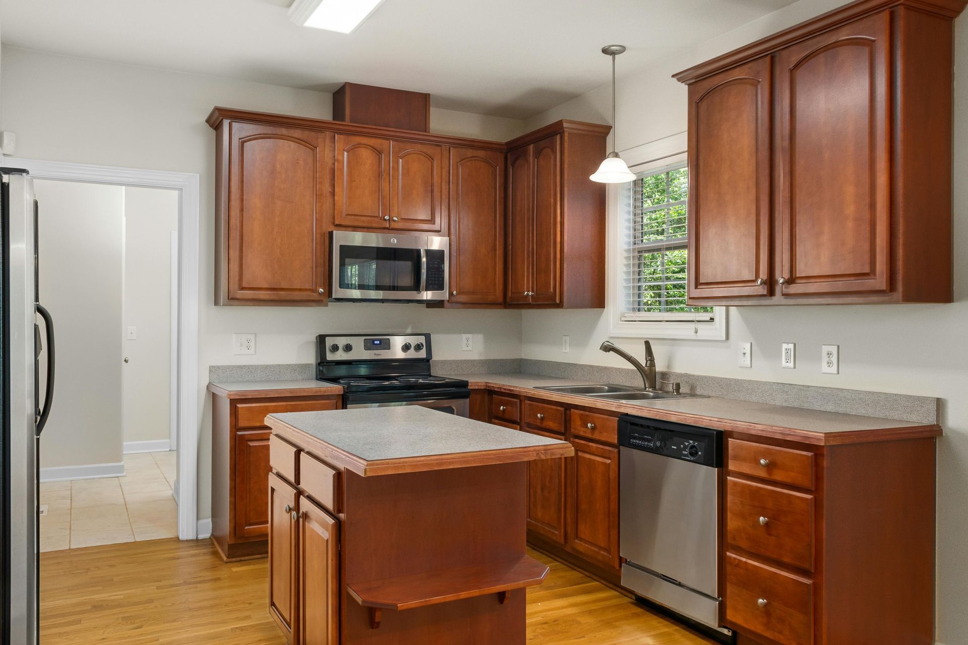 Kitchen with dark wood cabinets, stainless steel appliances, and island.