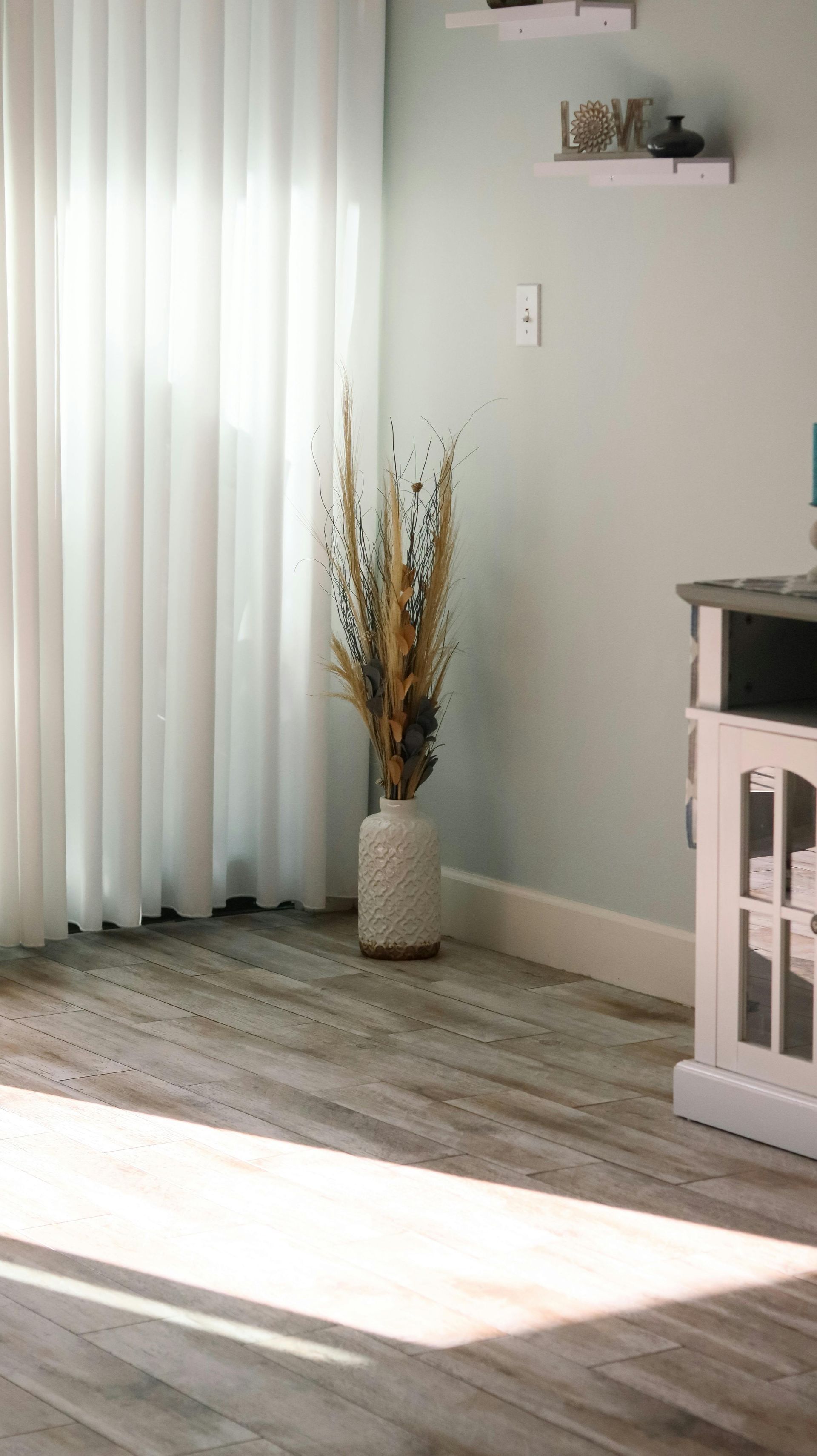 Wooden porch with teal siding and white trim. Broom leaning against the siding.