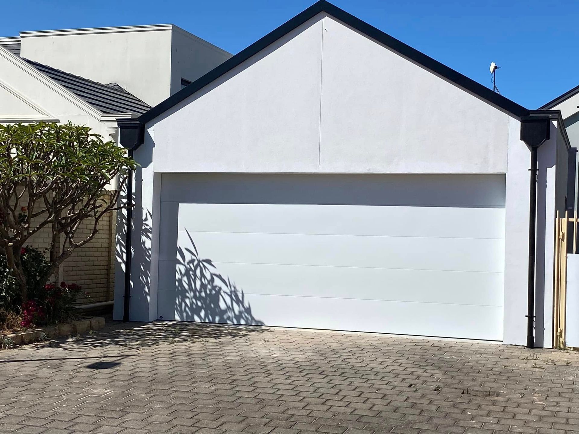 An open-fronted carport with a grey corrugated roof, wooden framing, and light-colored walls on a concrete pad.