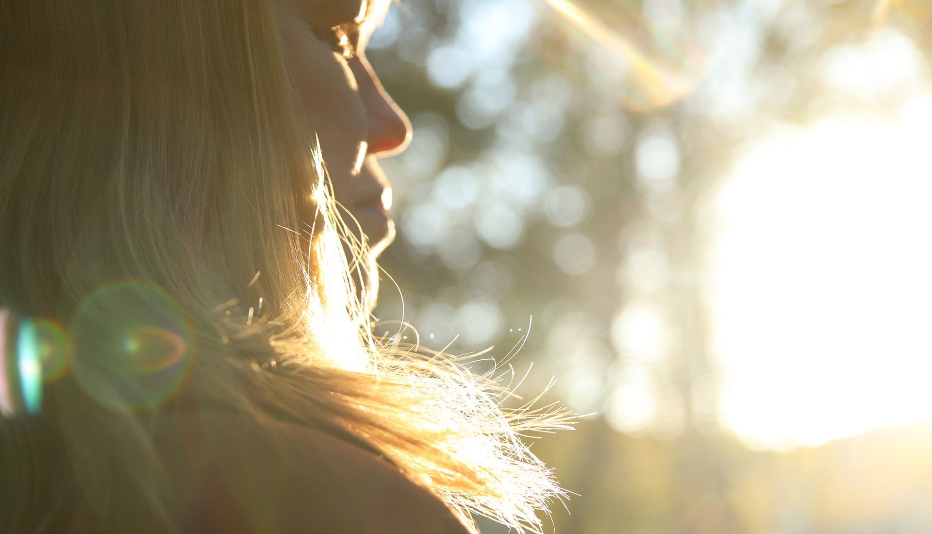 Woman with blonde hair, backlit by bright sun, looking off-screen.