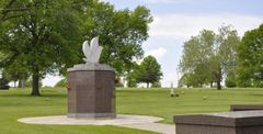 There is a statue of a dove in the middle of a cemetery.