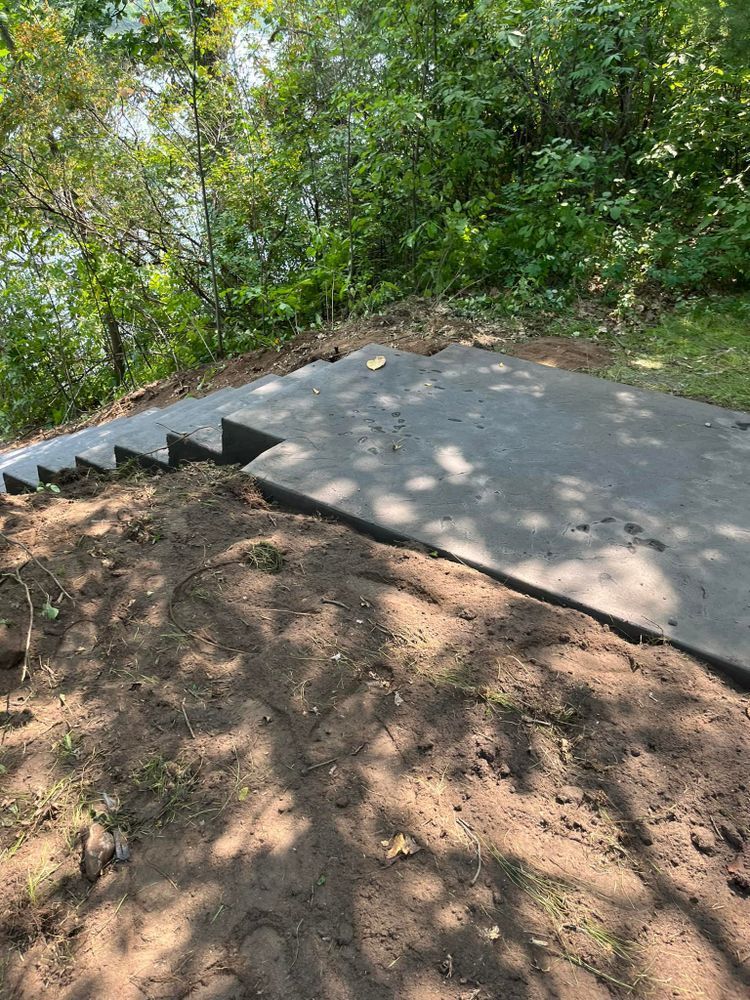 Concrete steps leading up a hillside, surrounded by dirt and greenery.