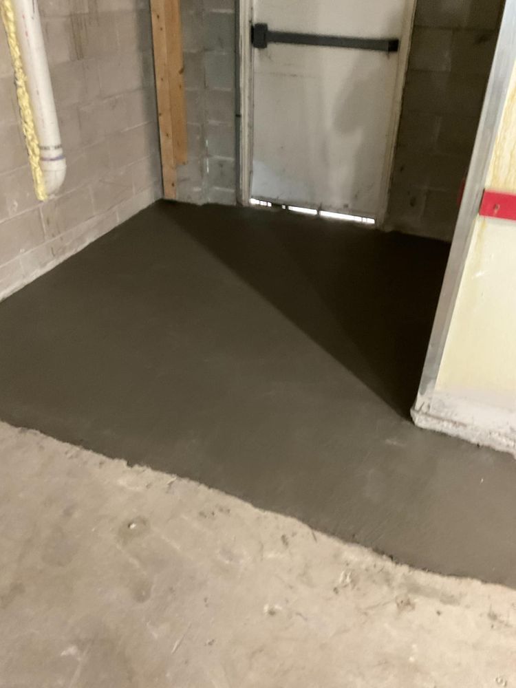 Newly poured concrete patch in a basement, near a door.