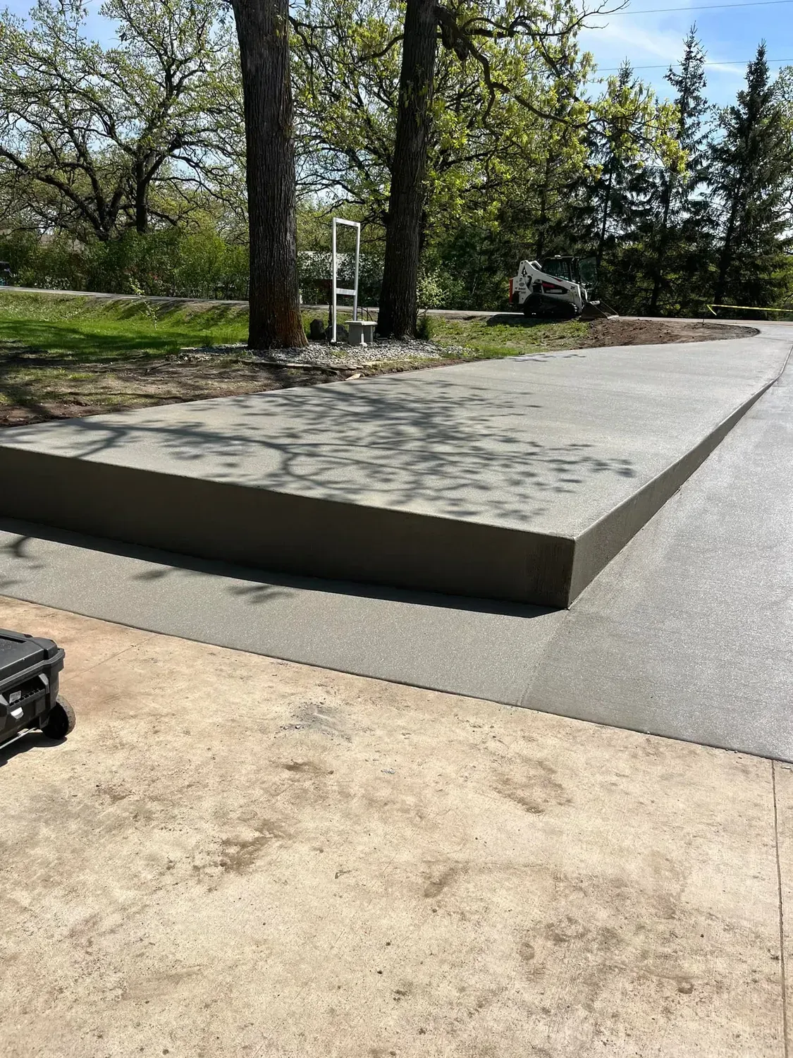 Concrete slab with a step, trees and greenery in the background.