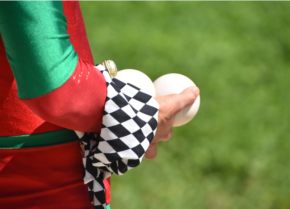 A man in a tuxedo and white gloves is holding a card in his pocket.
