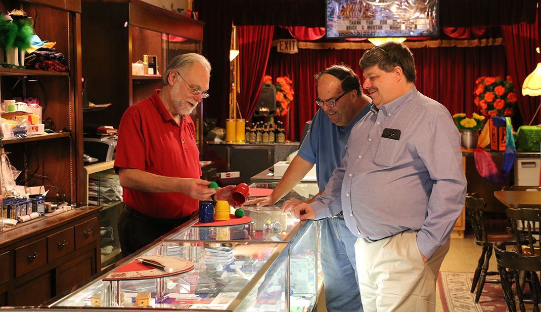 Three men are looking at a display case in a store.