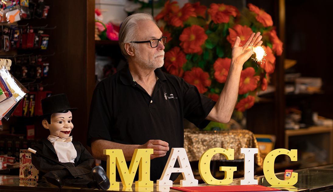 A man is standing in front of a sign that says magic.