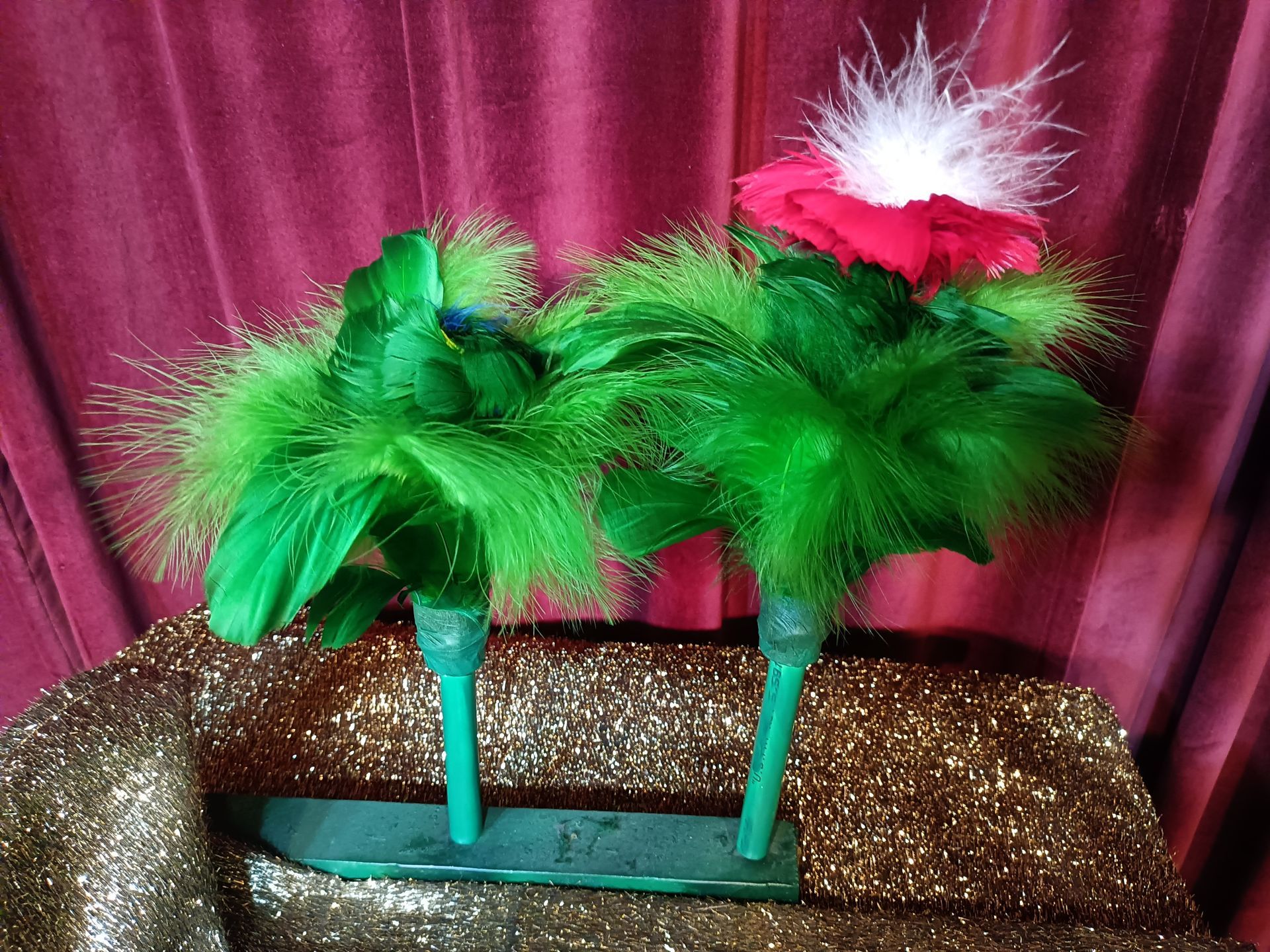 A pair of green high heels with feathers and flowers on them.
