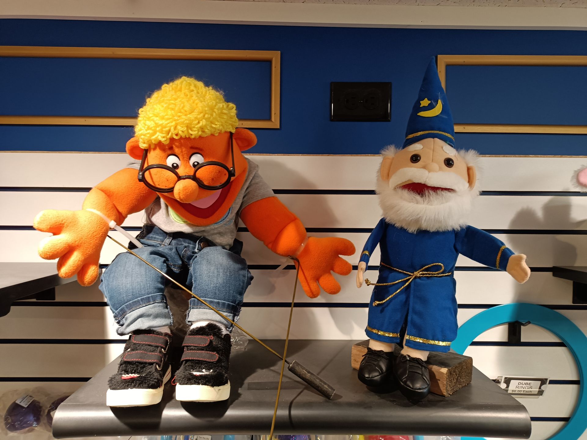 A gnome and a puppet are sitting on a shelf