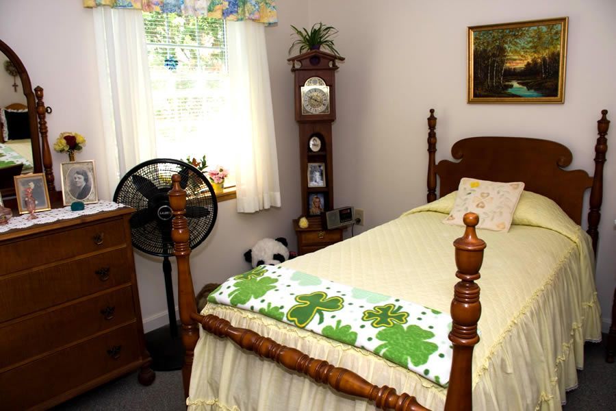 A bedroom with a single bed a dresser and a fan