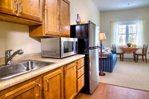 A kitchen with wooden cabinets , a sink , a microwave , and a refrigerator.