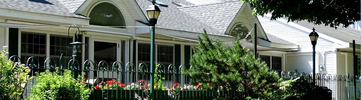 A house with a fence around it and trees in front of it.