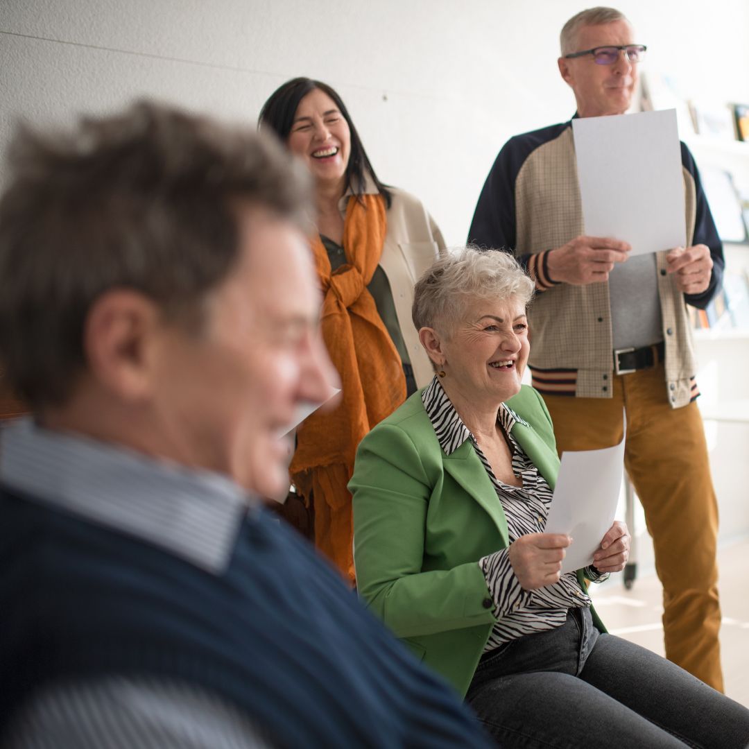 A group of people are laughing and one woman is wearing a green jacket