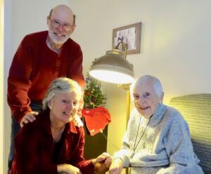 A man and two women are posing for a picture in a living room.