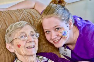 An elderly woman is laying on a couch with a nurse.