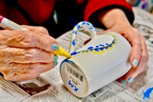 A person is painting a mug with a marker.