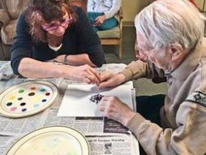 A man and a woman are sitting at a table painting.