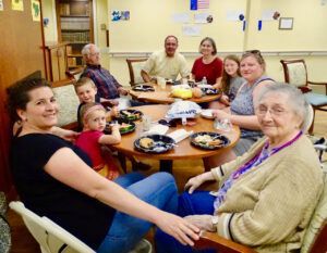 A group of people are sitting around a table with plates of food.