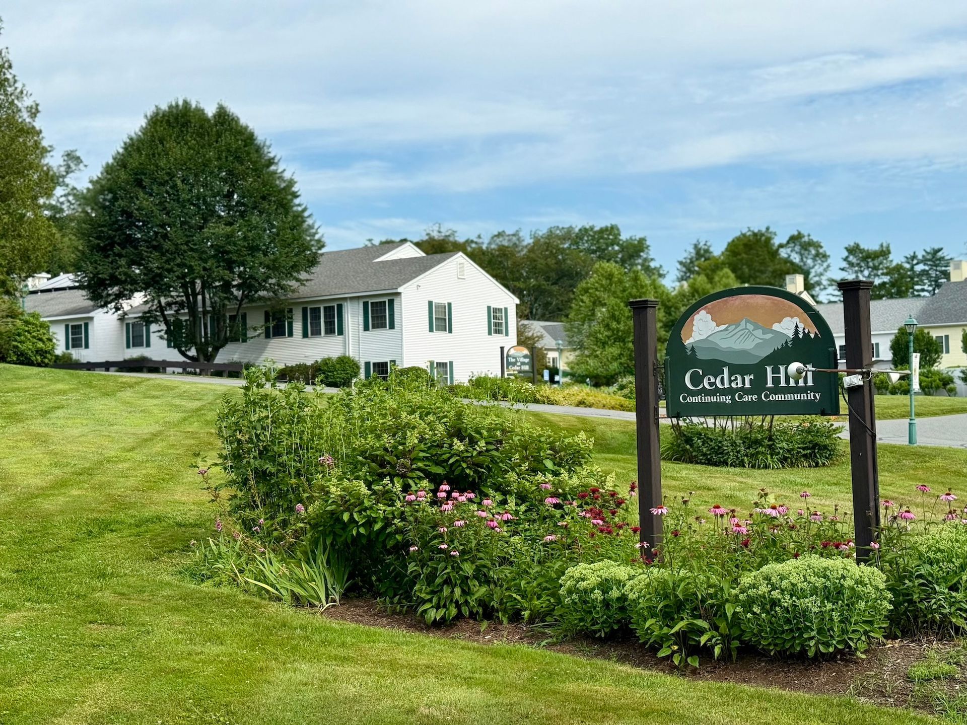 Cedar Hill Community sign with a white building and green landscape.