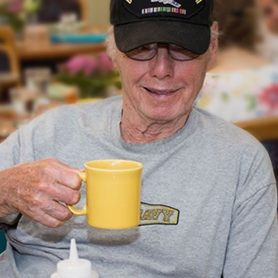 A man wearing a navy shirt is holding a yellow mug