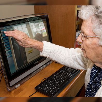 An elderly woman is using an acer computer
