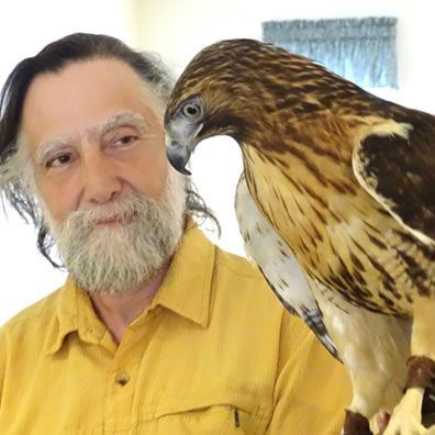 A man with a beard is holding a bird on his arm