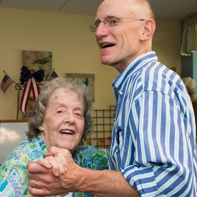 A man in a striped shirt is hugging an older woman